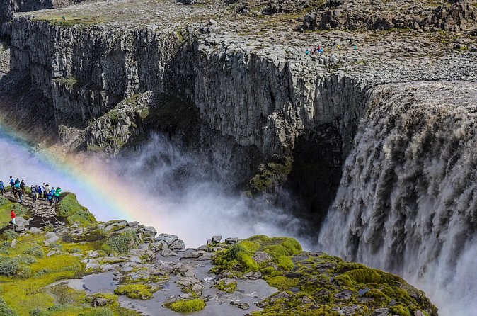 A grey torrent pouring into a basalt canyon, a rainbow in the spray